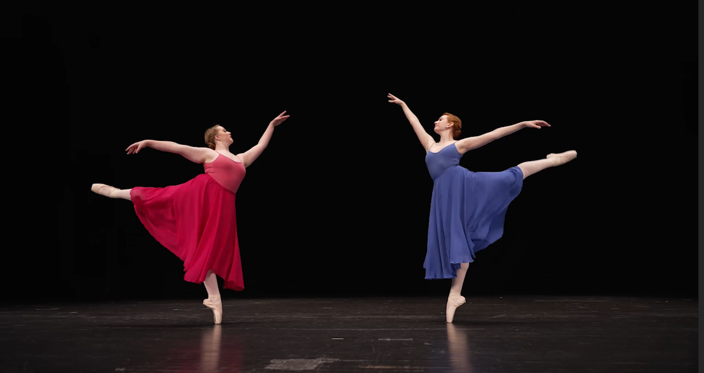 Two dancers posing dramatically in jewel tone dresses